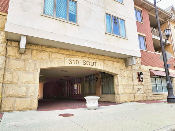 Front view of a multi-story building with stone facade and an archway entrance.