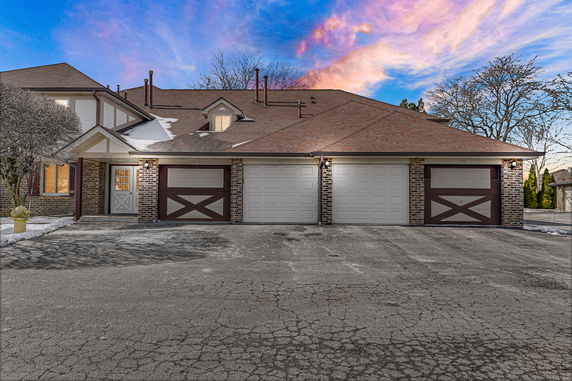 Front view of a multi-garage house with a brick exterior and brown roof.