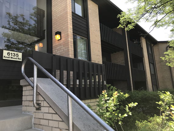 Front view of a multi-story apartment building with brick and dark wood paneling.