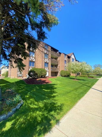 Front view of a multi-story brick apartment building with balconies.