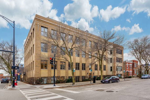 Front view of a multi-story building with a brick facade on a street corner.