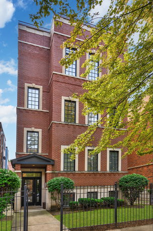 Front view of a multi-story brick building with large windows.