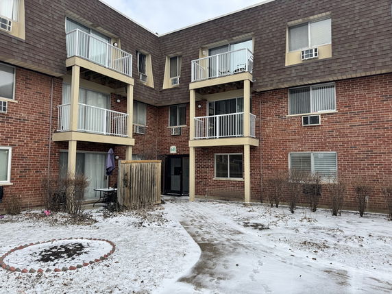 Front view of a multi-story building with balconies and brick exterior.