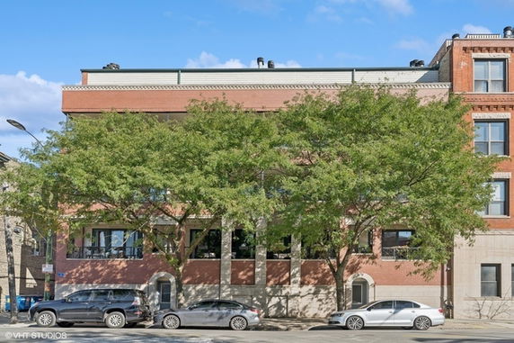 Front view of a brick building with multiple windows and trees partially obscuring the structure.