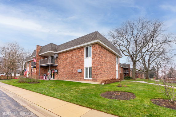 Front view of a two-story brick building with balconies and a sloped roof.