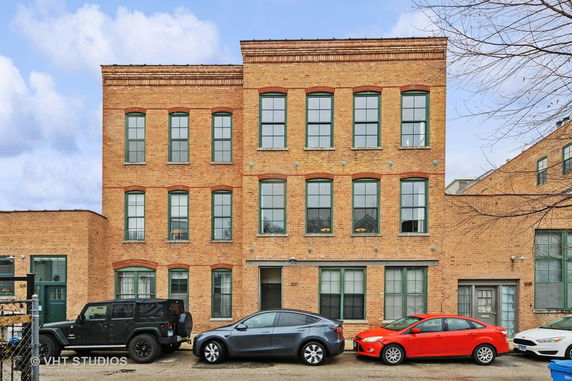 Front view of a three-story brick building with multiple windows.