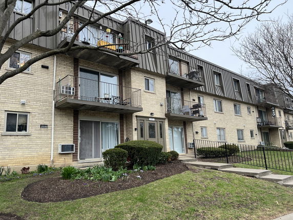Front view of a multi-story apartment building with balconies.