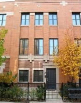Front view of a three-story brick townhouse with large windows.
