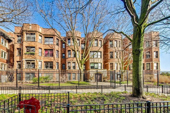 Front view of a multi-story brick apartment building with bay windows.