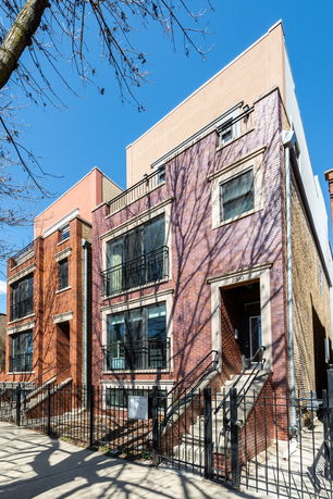 Front view of a multi-story brick house with balconies.