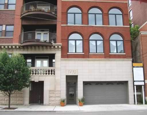 Front view of a multi-story building with a garage and large windows.