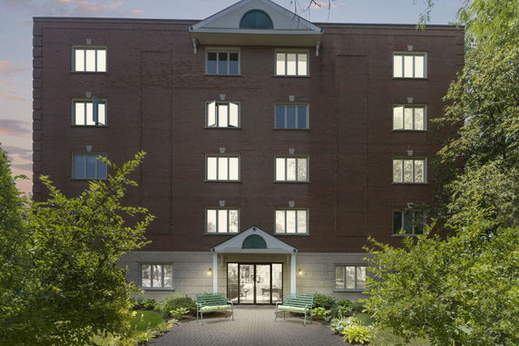 Front view of a multi-story brick building with large windows and a central entrance.