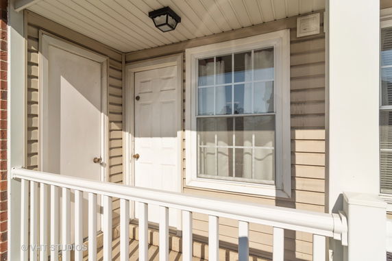 Front view of a residential entrance with a white railing, door, and window.