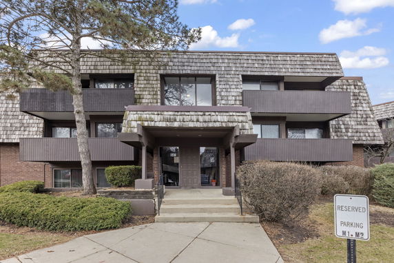 Front view of a multi-story building with balconies and a shingled roof.
