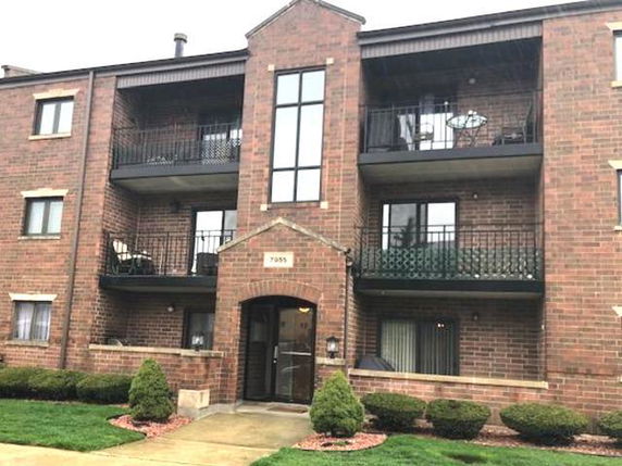 Front view of a multi-story brick apartment building with balconies.