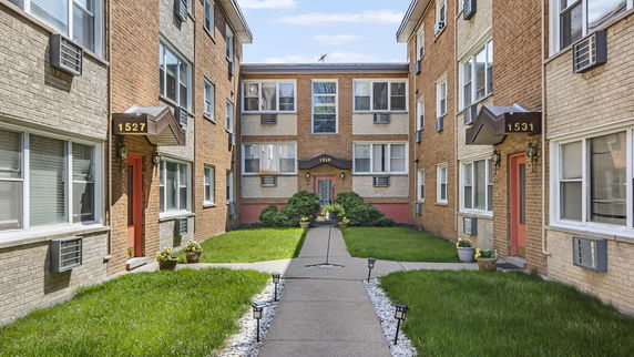 Front view of a multi-story apartment building with brick exterior.