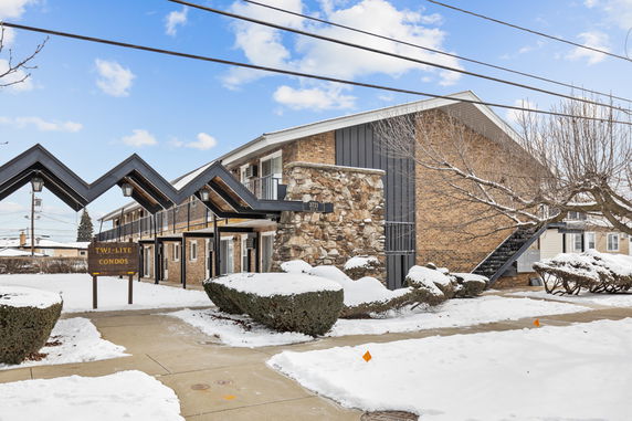 Front view of a two-story condominium building with stone and brick exterior.