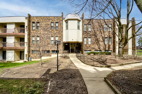 Front view of a multi-story building with brick facade and balconies.