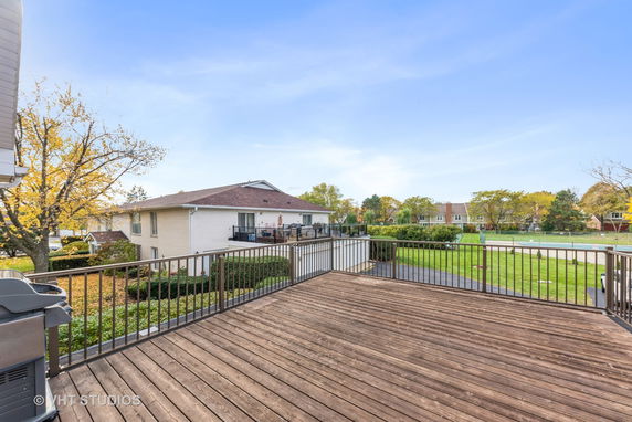 Panoramic view from a wooden deck overlooking residential buildings and greenery.