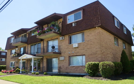 Front view of a multi-story apartment building with balconies and brown exterior.