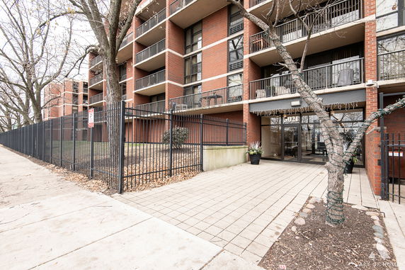 Front view of a multi-story brick building with balconies and a gated entrance.