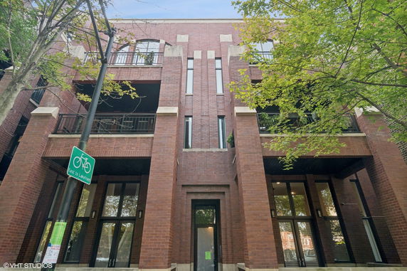Front view of a multi-story brick building with balconies and large windows.