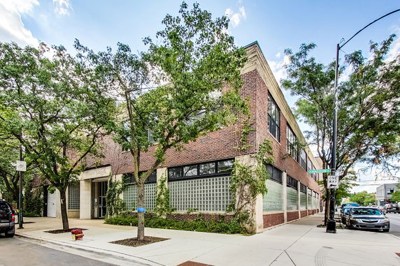 Front view of a two-story brick building with large glass block windows and climbing greenery.