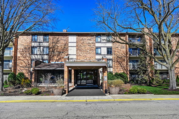 Front view of a multi-story brick building with a central entrance and balconies.