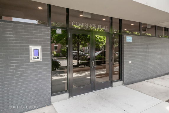 Front view of a building entrance with glass doors and dark brick facade.