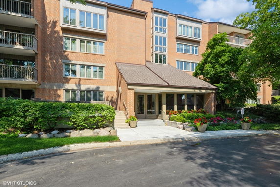 Front view of a multi-story brick building with balconies and a covered entrance.