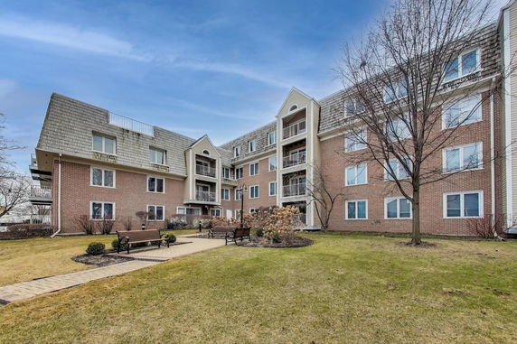 Front view of a multi-story apartment building with balconies and a sloped roof.