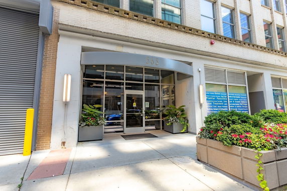 Front view of a commercial building entrance with glass doors and planters.