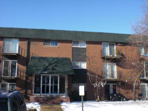 Front view of a three-story brick apartment building with balconies.