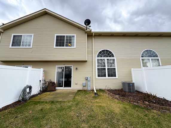 Rear view of a two-story house with large windows and siding exterior.
