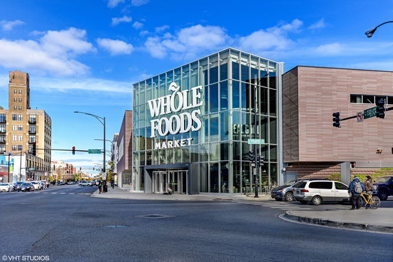 Front view of a modern building with large glass windows and a visible sign.