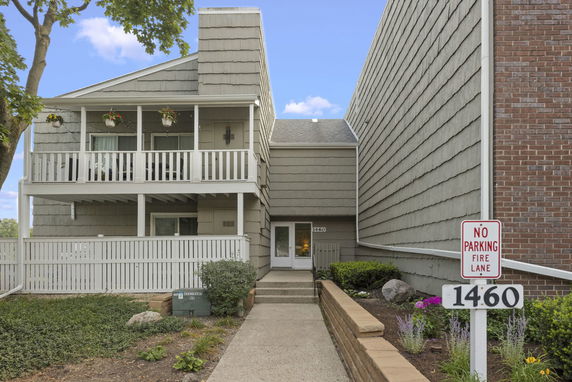 Front view of a two-story building with a balcony and a walkway leading to the entrance.