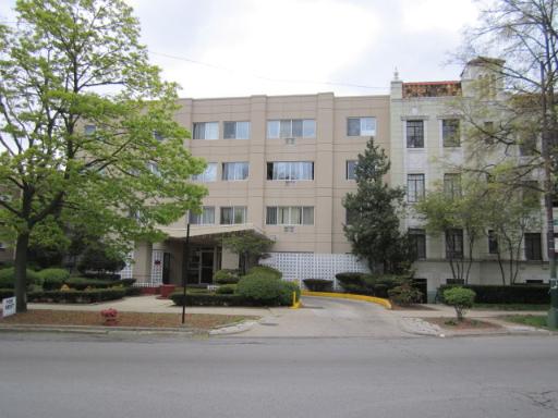 Front view of a multi-story building with a beige facade and several windows.