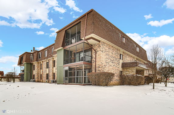 Front view of a multi-story building with brick and wood paneling.