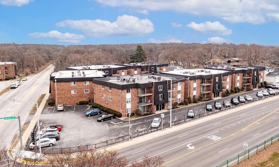 Front view of a multi-story brick apartment complex with a parking area.