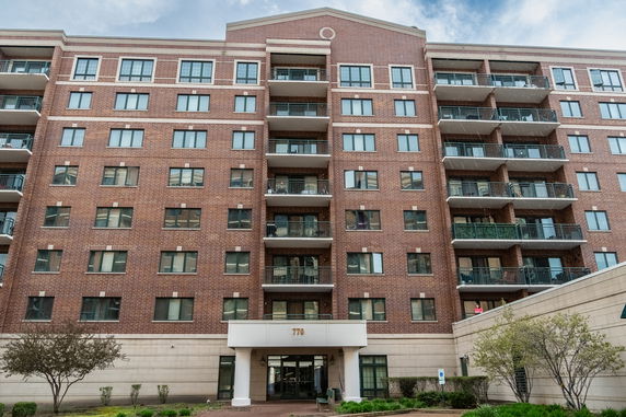 Front view of a multi-story brick apartment building with balconies.