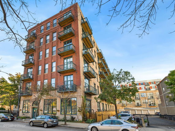 Front view of a multi-story brick apartment building with balconies.