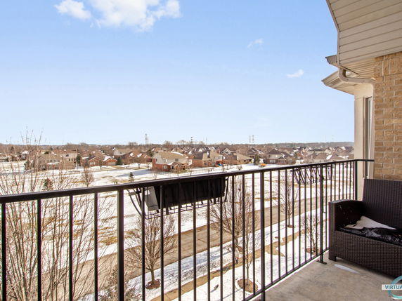 View from a building balcony overlooking a suburban neighborhood covered in light snow.