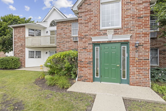 Front view of a two-story brick house with a green door and small balcony.