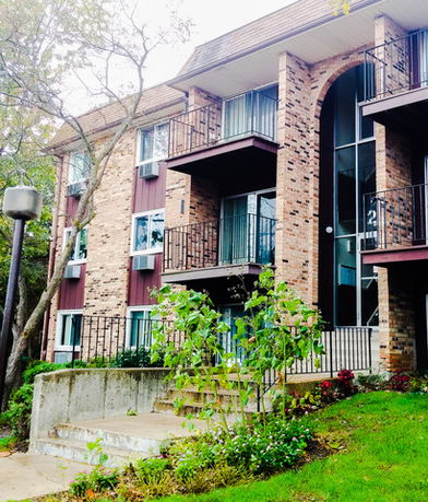 Front view of a multi-story brick apartment building with balconies.