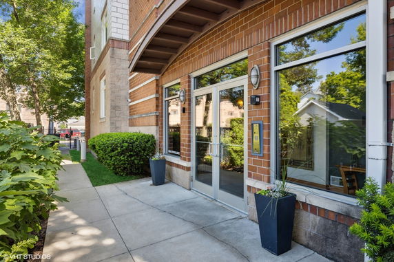 Front view of a brick building entrance with large windows.