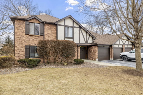Front view of a two-story house with a brown brick exterior and a three-car garage.