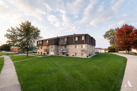 Front view of a multi-story residential building with balconies and brick exterior.