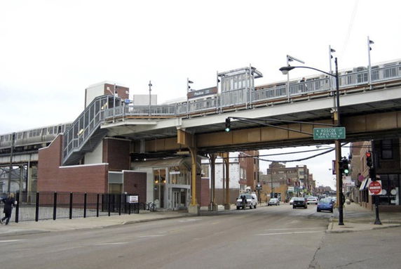 Side view of an elevated train station with a staircase leading up to the platform.