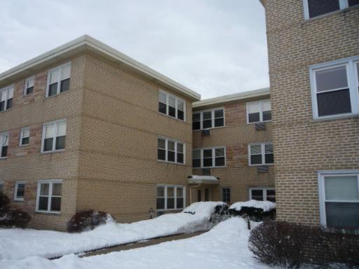 Front view of a multi-story brick apartment building with snow on the ground.