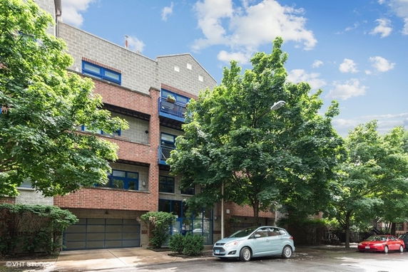 Front view of a multi-story residential building with large trees in front.